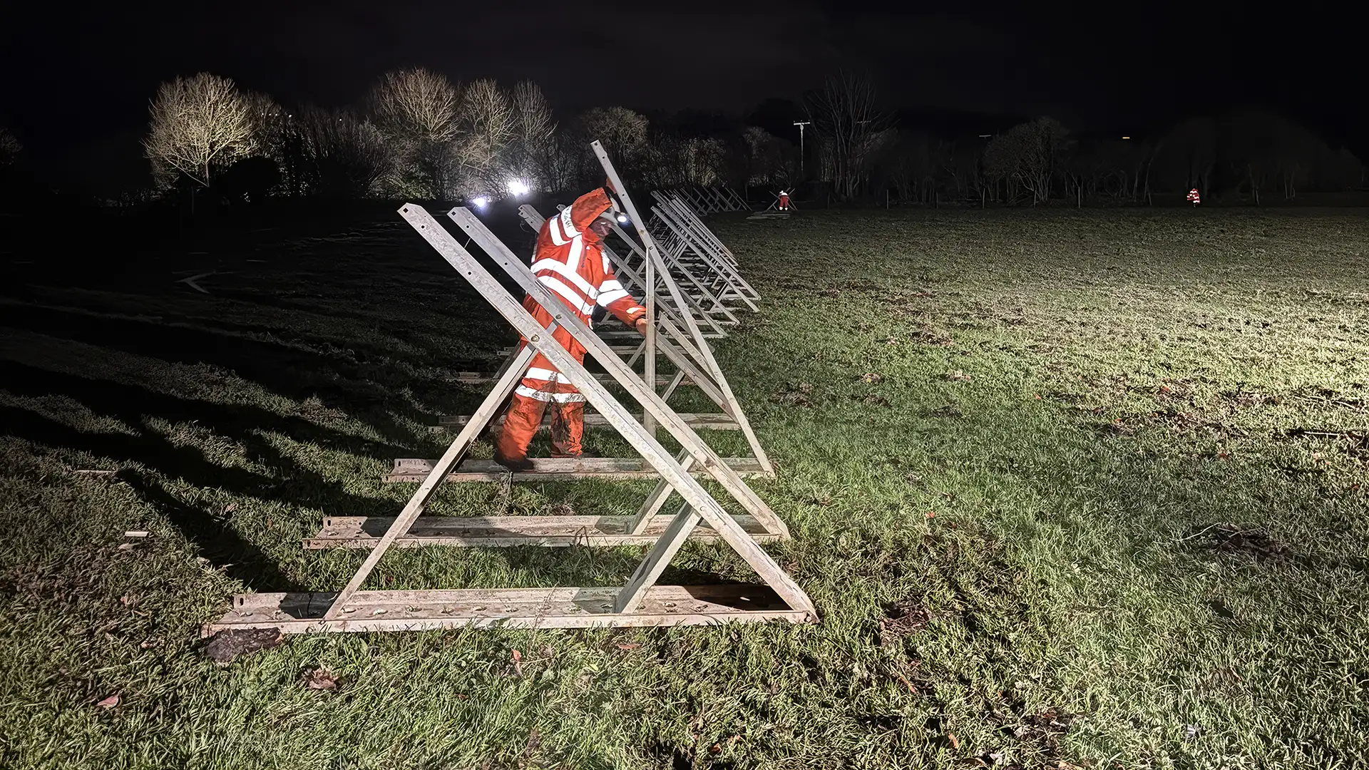 Operative installing temporary flood defence support frames during emergency night works