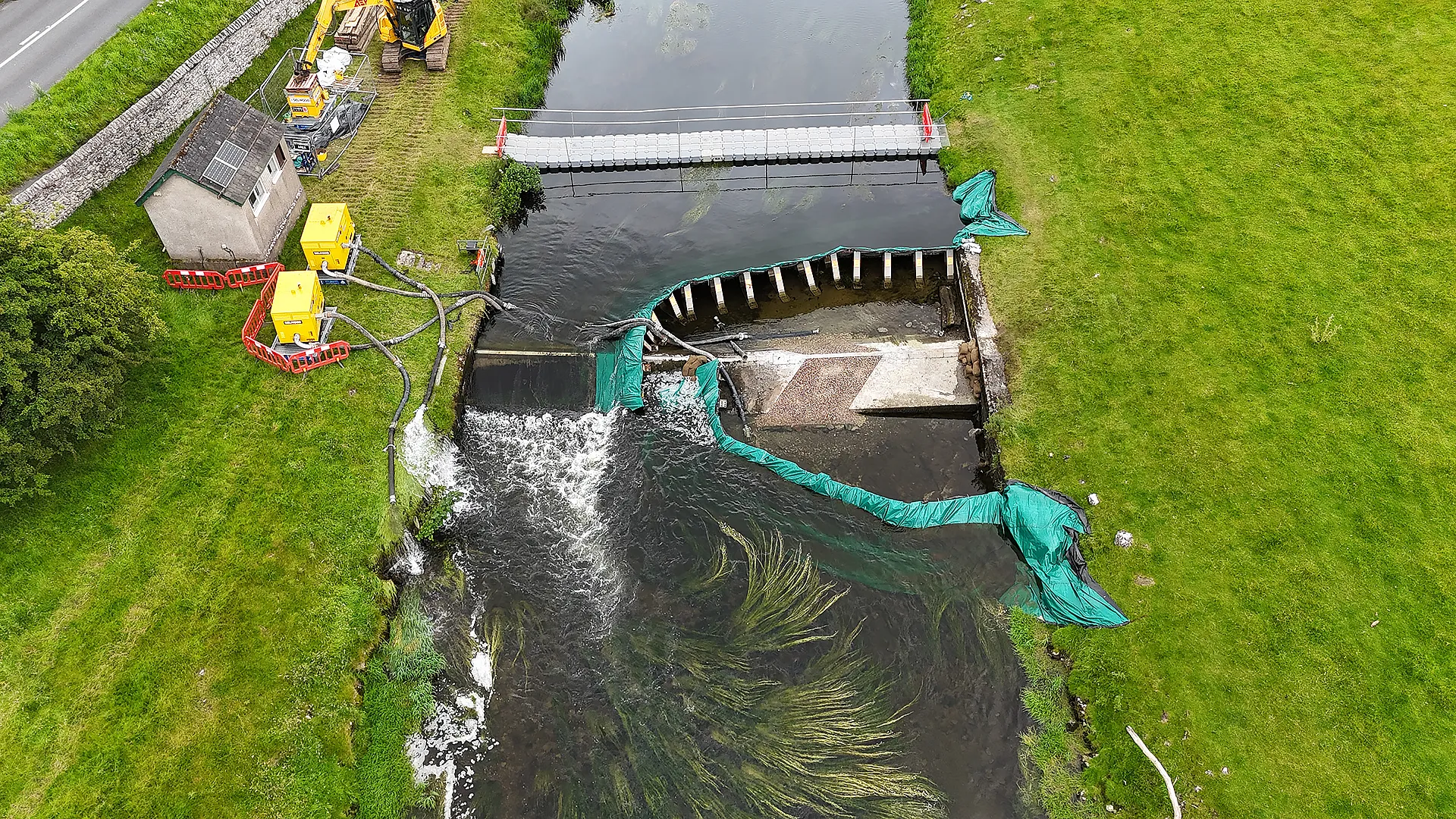 Aerial view of a frame dam with over pumping equipment installed.