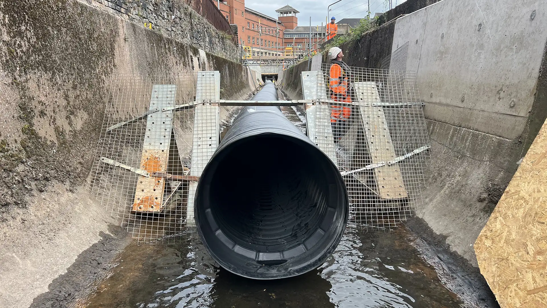 Large diameter temporary flow diversion pipeline installed within a drainage channel to bypass water during infrastructure works.