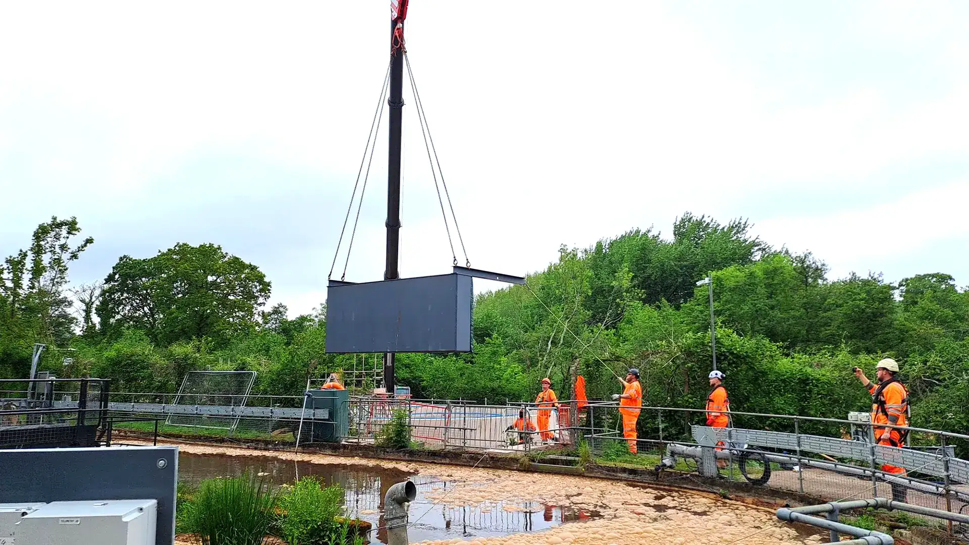 Crane lifting a temporary water control structure into position at a water treatment site